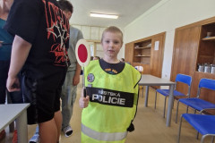 Chlapec v policejní vestě s plácačkou.