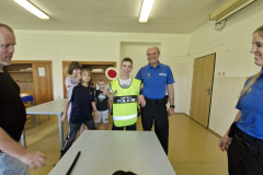 Chlapec v policejní vestě s plácačkou.