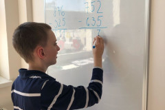 Chlapec počítá příklad na tabuli.