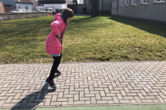 Dívka skáče panáka na školním hřišti.