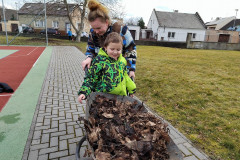 Chlapec s paní asistentkou odváží listí na kolečkách.