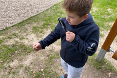 Chlapec venku lupou zkoumá přírodu.