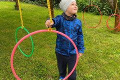 Chlapec u zavěšených kruhů v jabloňovém sadu.