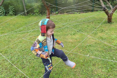 Chlapec prolézá pavučinou mezi stromy.