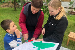 Chlapec s paní asistentkou malují společný třídní obraz.