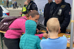Žáci s paní učitelkou zkoumají zbraň u policejního stánku na Dni dětí.