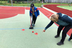 Chlapec posouvá koštětem míček po zemi.