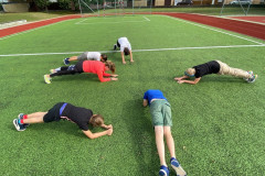 Třída dělá vzpor na loktech venku na hřišti.