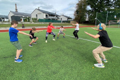 Třída dělá dřepy venku na hřišti.