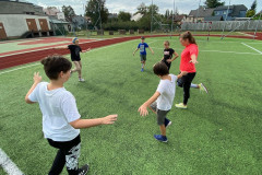 Třída dělá stoj na jedné noze venku na hřišti.