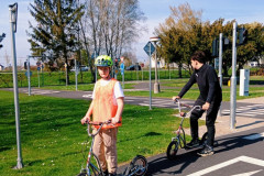 Chlapec a pan asistent na koloběžkách na dopravním hřišti.