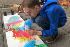 Chlapec fouká barevné bubliny na výkres.