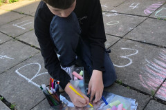 Chlapec na školní zahradě pracuje s křídami.