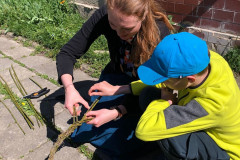 Chlapec s paní učitelkou plete velikonoční pomlázku.