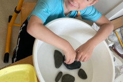 Chlapec zkoumá kameny v misce s vodou.