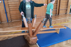 Třída v zelené při tělocviku na provizorní houpačce.