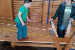 Třída v zelené při tělocviku na provizorní houpačce.