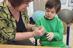 Chlapec v zelené pracuje s paní asitentkou.