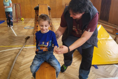 Chlapec v tělocvičně na skluzavce z lavičky.