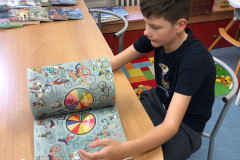 Chlapec si v knihovně prohlíží  knihu.