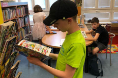 Chlapec si v knihovně prohlíží komiks.