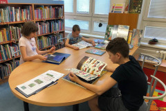 Žáci  si v knihovně prohlíží knihy.