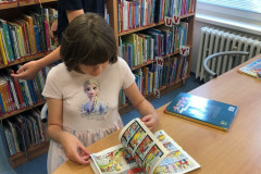 Dívka si v knihovně prohlíží komiks.