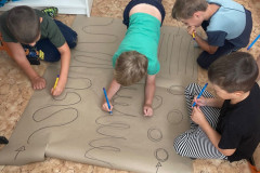 Chlapci trénují grafomotoriku na velkém papíře.