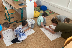 Chlapci trénují grafomotoriku na velkém papíře.