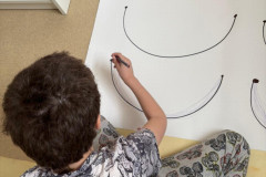 Chlapec trénuje grafomotoriku na velkém papíře.