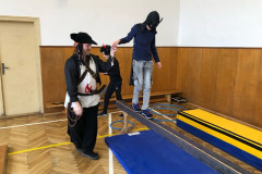 Chlapec s panem asistentem v kostýmu v tělocvičně na překážkové dráze.