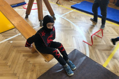 Chlapec v kostýmu v tělocvičně na překážkové dráze.