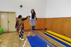 Dívka s paní asistentkou v kostýmu v tělocvičně na překážkové dráze.