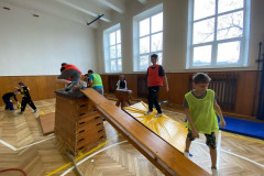 Žáci v kostýmech  v tělocvičně na překážkové dráze.