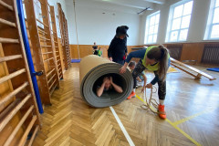 Žáci v kostýmech  v tělocvičně na překážkové dráze.