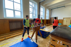 Žáci v kostýmech sportovců  v tělocvičně na překážkové dráze.