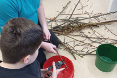 Chlapec s panem asistentem stříhá větve.