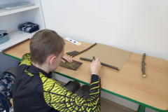 Chlapec skládá větve na karton.