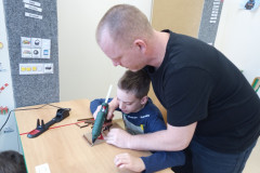 Chlapec s panem asistentem lepí větvičku na karton.