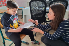 Paní učitelka předává chlapci vysvědčení.