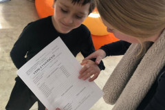 Paní učitelka předává chlapci vysvědčení.