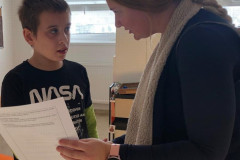 Paní učitelka předává chlapci vysvědčení.