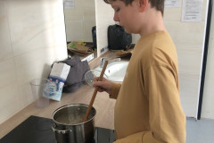 Chlapec míchá v hrnci na plotně.