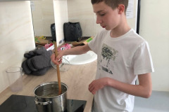 Chlapec míchá v hrnci na plotně.