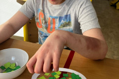 Chlapec výtvarně tvoří ze zelených papírků.