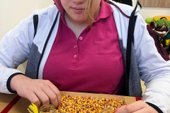 Dívka trénuje jemnou motoriku se zrnky kukuřice.