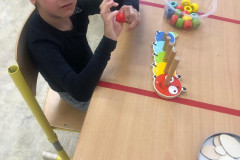 Chlapec navléká korálky na dřevěné trny.