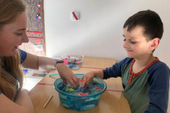 Chlapec zkoumá předměty v misce s vodou.