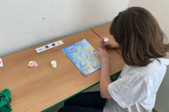 Dívka ve výtvarce lepí ptáčky na výkres.