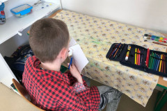 Chlapec ve výtvarce stříhá.